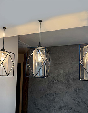 Textured plaster wall lit by geometric pendant fixtures